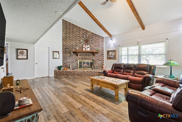 living room with light hardwood / wood-style floors, a textured ceiling, beam ceiling, high vaulted ceiling, and a fireplace