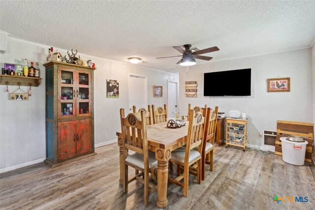 dining room featuring a textured ceiling, crown molding, ceiling fan, and light hardwood / wood-style flooring