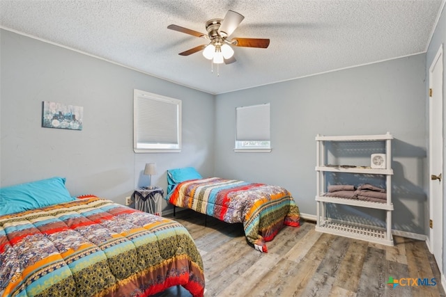 bedroom featuring ceiling fan, wood-type flooring, and a textured ceiling