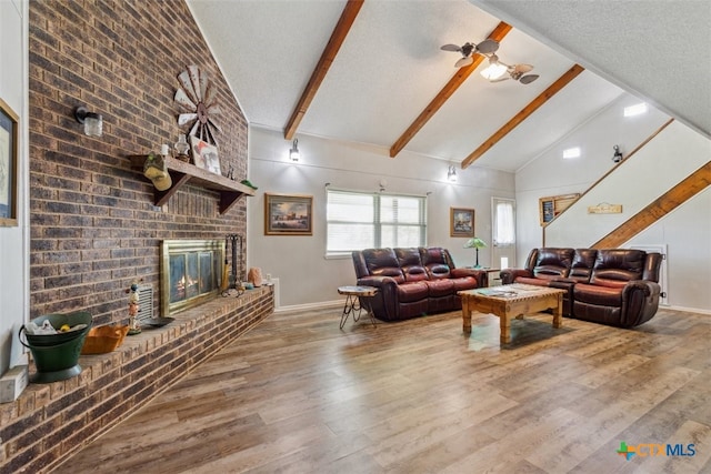 living room featuring a brick fireplace, hardwood / wood-style flooring, high vaulted ceiling, ceiling fan, and beam ceiling