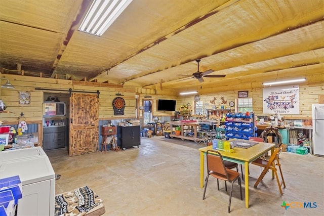 dining room with a barn door, a workshop area, and wood walls