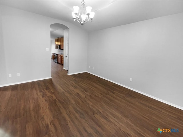 spare room with a chandelier and dark wood-type flooring