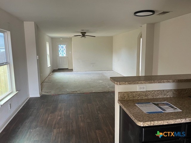 1421 Breanna Ln, Kyle, TX 78640 - unfurnished living room with dark wood-style flooring, arched walkways, baseboards, and a ceiling fan