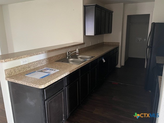 1421 Breanna Ln, Kyle, TX 78640 - kitchen featuring a sink, dark wood finished floors, a peninsula, and dark cabinetry
