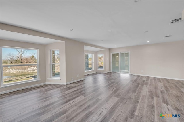 unfurnished living room with recessed lighting, wood finished floors, visible vents, and baseboards