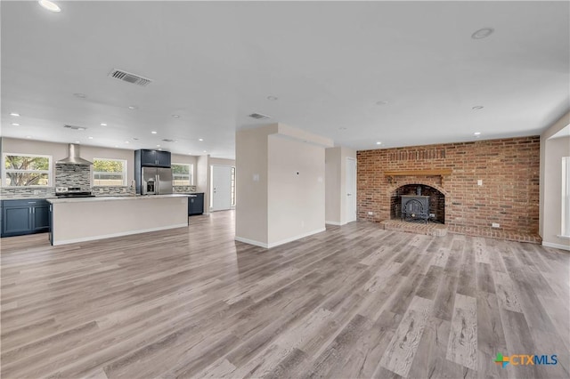 unfurnished living room featuring brick wall, recessed lighting, visible vents, and light wood-style floors