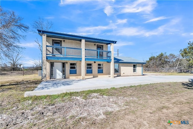 back of house with a patio area, brick siding, and a balcony