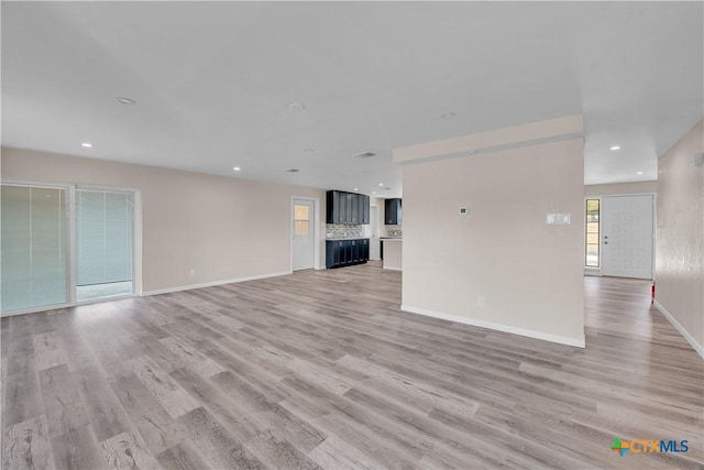 unfurnished living room with light wood-type flooring, baseboards, and recessed lighting