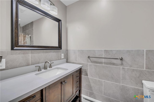 full bath featuring toilet, a wainscoted wall, vanity, and tile walls