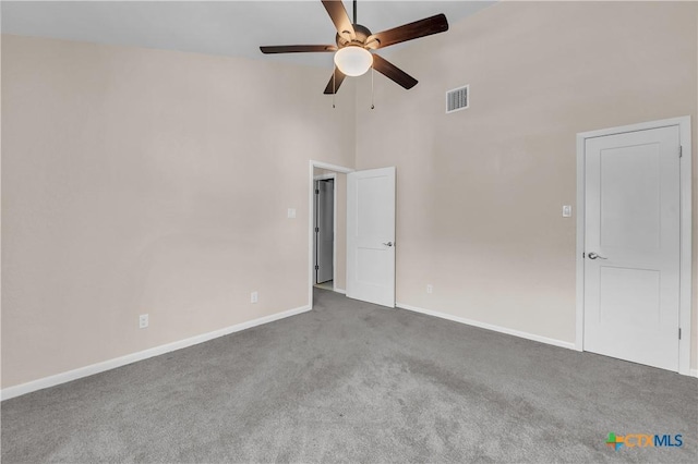 unfurnished room featuring ceiling fan, carpet flooring, a towering ceiling, visible vents, and baseboards