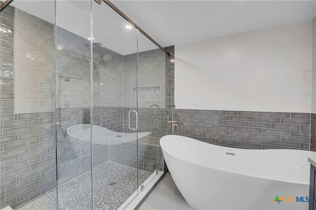 full bath with a stall shower, a freestanding bath, tile walls, and tile patterned floors