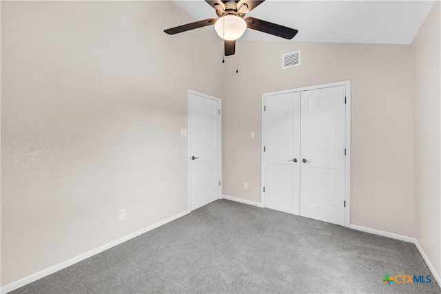 unfurnished bedroom with lofted ceiling, carpet floors, visible vents, baseboards, and a closet