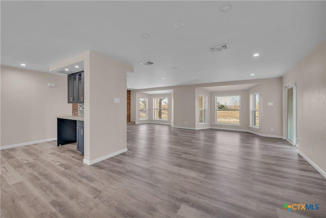 unfurnished living room with baseboards, wood finished floors, visible vents, and recessed lighting