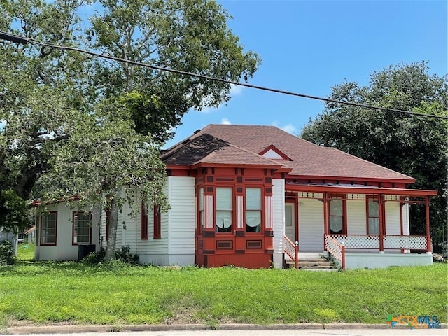 view of front of home with cooling unit, a porch, and a front yard