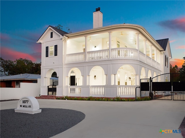 exterior space with a standing seam roof, a gate, metal roof, a balcony, and a chimney