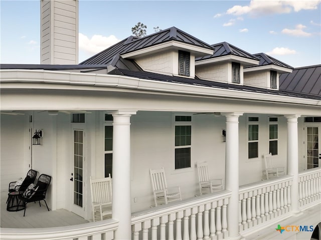 view of side of property with a chimney, a porch, metal roof, and a standing seam roof