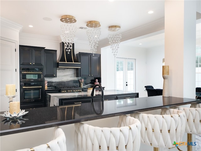 kitchen with a breakfast bar, ornamental molding, dark stone countertops, backsplash, and custom exhaust hood