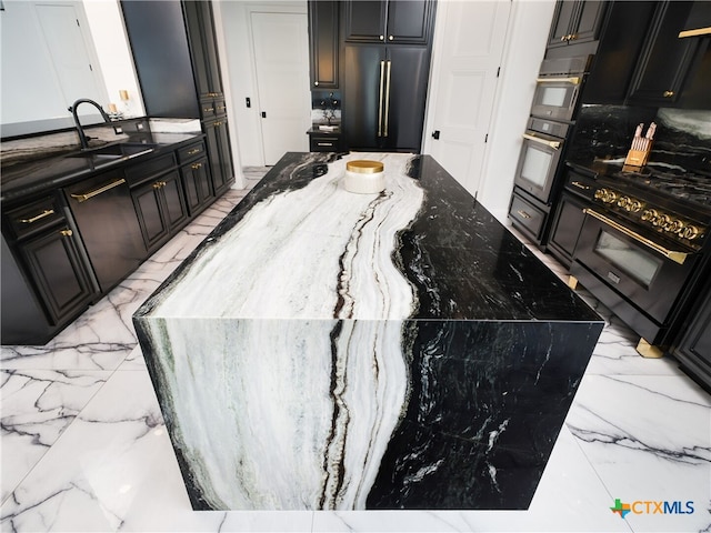 kitchen featuring stone countertops, marble finish floor, built in fridge, and a sink