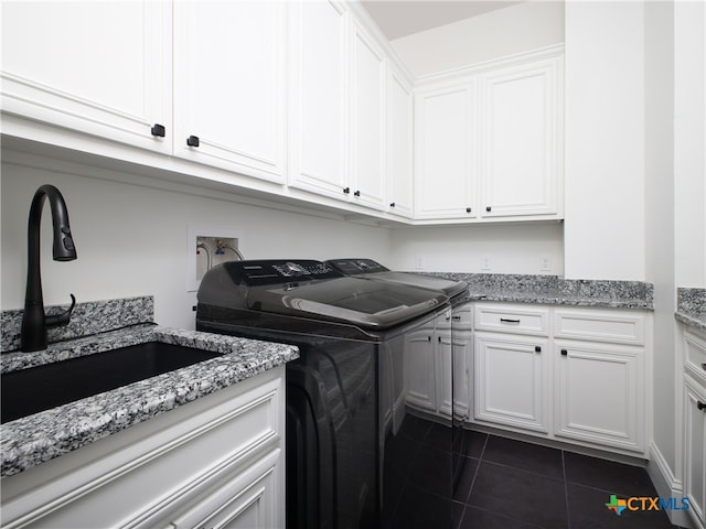 laundry area featuring separate washer and dryer, cabinet space, dark tile patterned flooring, and a sink