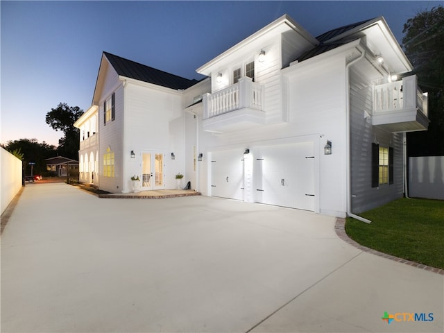 exterior space with a standing seam roof, concrete driveway, french doors, a garage, and metal roof