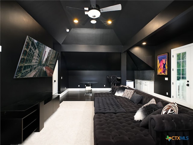 cinema room featuring a ceiling fan, vaulted ceiling, wood finished floors, and baseboards