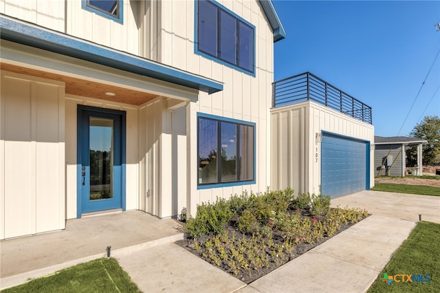 property entrance with a garage, board and batten siding, and a balcony