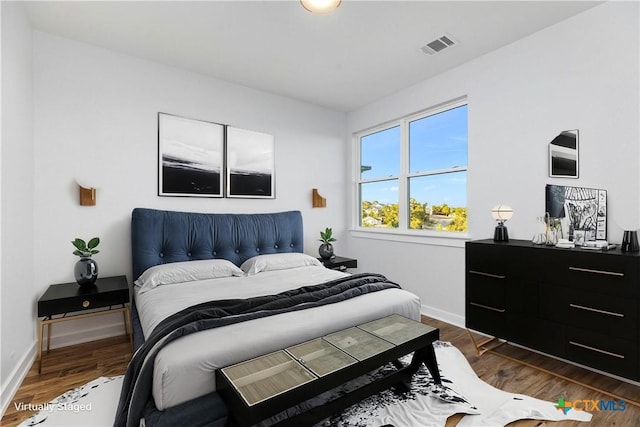 bedroom with visible vents, baseboards, and dark wood-style floors