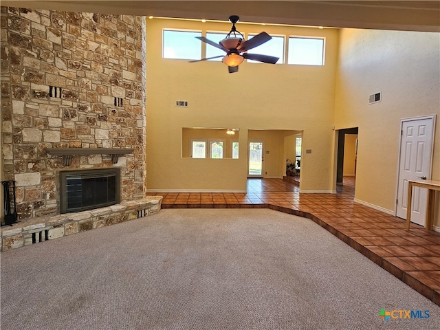 unfurnished living room featuring a high ceiling, carpet flooring, ceiling fan, and a fireplace