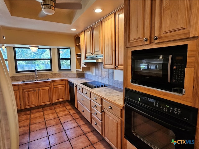 kitchen featuring tile countertops, tile patterned flooring, sink, black appliances, and a raised ceiling