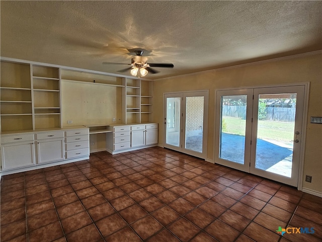 unfurnished living room featuring a textured ceiling, ornamental molding, ceiling fan, dark tile patterned floors, and built in desk