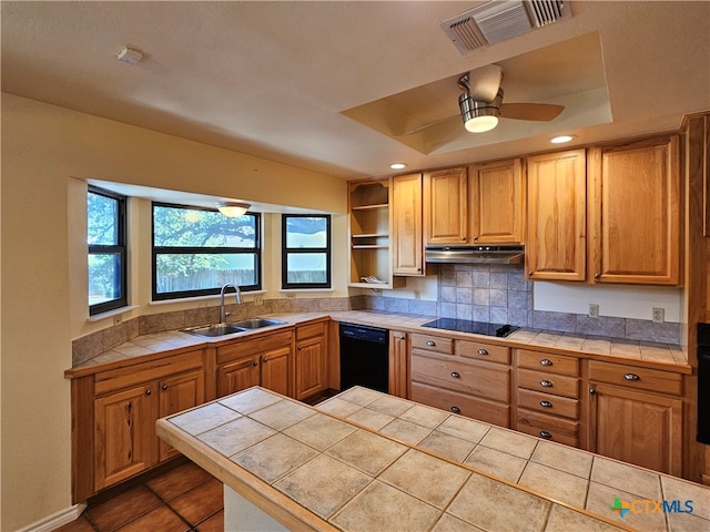 kitchen featuring tile counters, black appliances, sink, and a tray ceiling