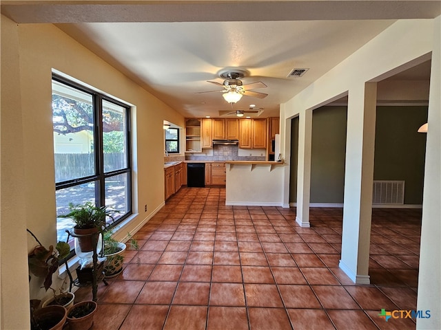 kitchen featuring a kitchen bar, black dishwasher, kitchen peninsula, ceiling fan, and light tile patterned flooring