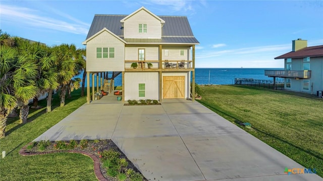 view of front facade featuring a balcony, a water view, a front yard, and a garage