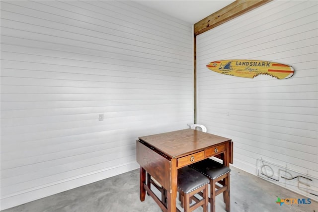 dining space with wooden walls and concrete floors