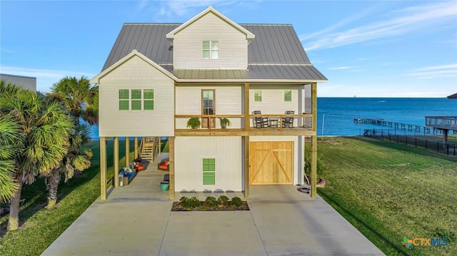 view of front of home featuring a front lawn, a water view, and a garage