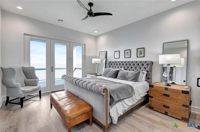 bedroom featuring access to exterior, ceiling fan, a water view, and light wood-type flooring