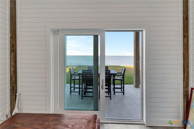 entryway with a wealth of natural light, a water view, and wooden walls