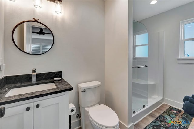 bathroom featuring hardwood / wood-style flooring, a shower with door, vanity, and toilet