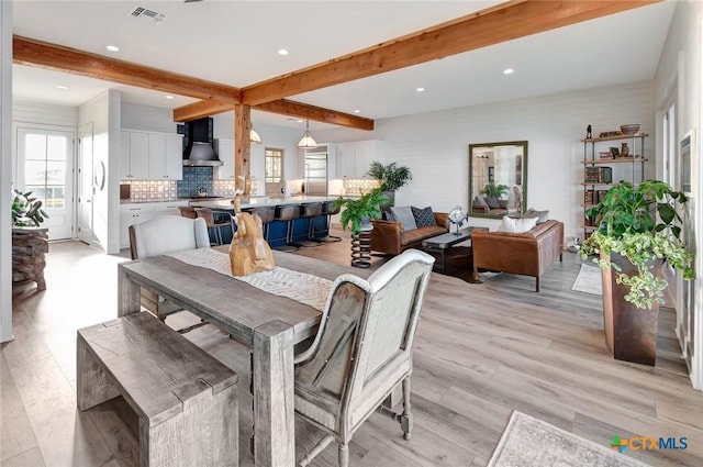 dining room with beamed ceiling and light wood-type flooring