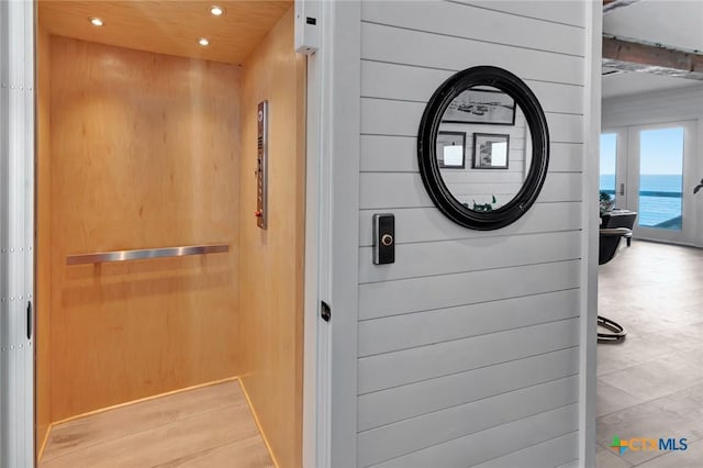 interior details featuring elevator, wooden walls, and french doors