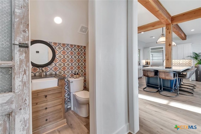 bathroom with beamed ceiling, vanity, toilet, and wood-type flooring