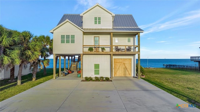 coastal inspired home featuring a front yard, a water view, a garage, and a carport