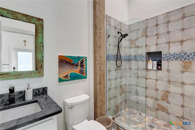 bathroom featuring a tile shower, vanity, and toilet