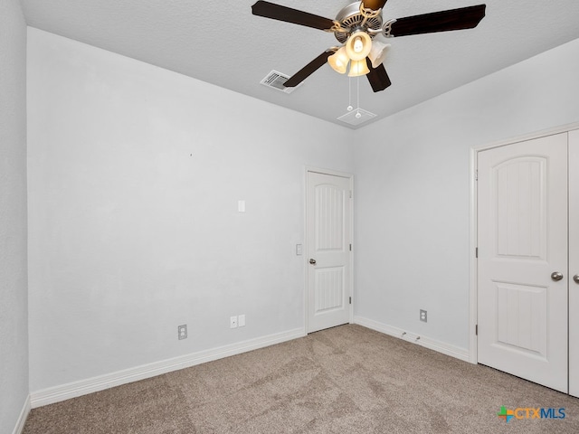 carpeted spare room with a textured ceiling and ceiling fan