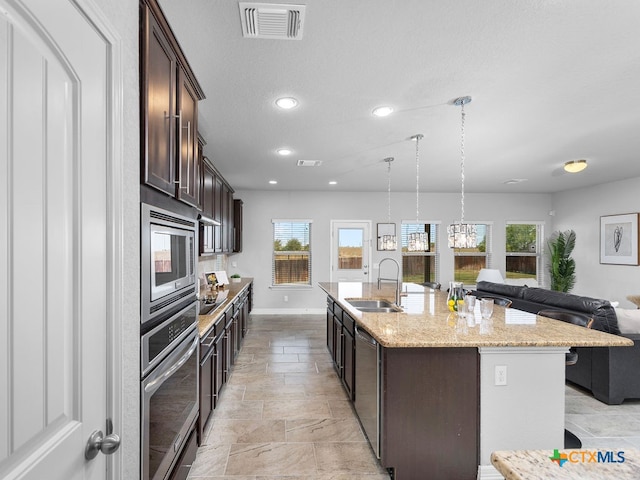 kitchen featuring a wealth of natural light, appliances with stainless steel finishes, sink, and a kitchen island with sink