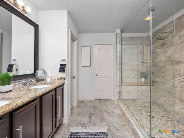 bathroom with vanity, a textured ceiling, and a tile shower