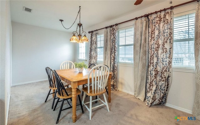 carpeted dining area featuring an inviting chandelier and a wealth of natural light