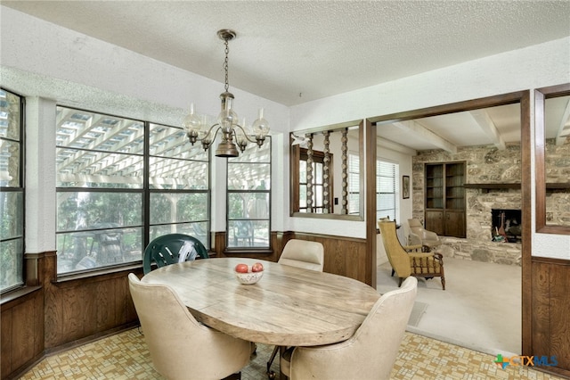 1104 Saint Williams Ave, Round Rock, TX 78681 - dining area featuring wooden walls, a chandelier, a textured ceiling, built in shelves, and a fireplace
