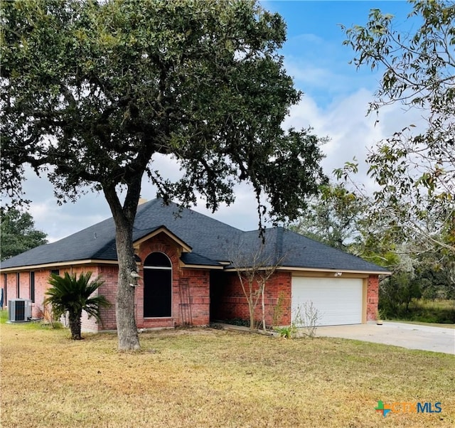 ranch-style home featuring central air condition unit, a front yard, and a garage