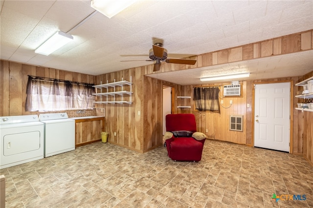 interior space featuring an AC wall unit, wood walls, washing machine and dryer, and ceiling fan